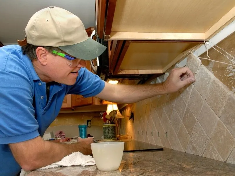 One of our tilers with a lovely outdoor hat pasting square tiles in the kitchen. Tiles colour cream