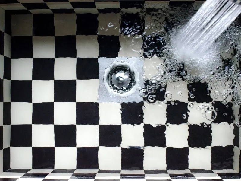 Black and white tiles in a kitchen sink in canberra with water running on it