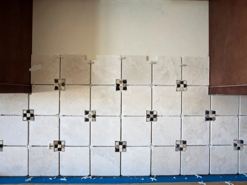 cream tiles with black and cream mosaics and brown cabinete
